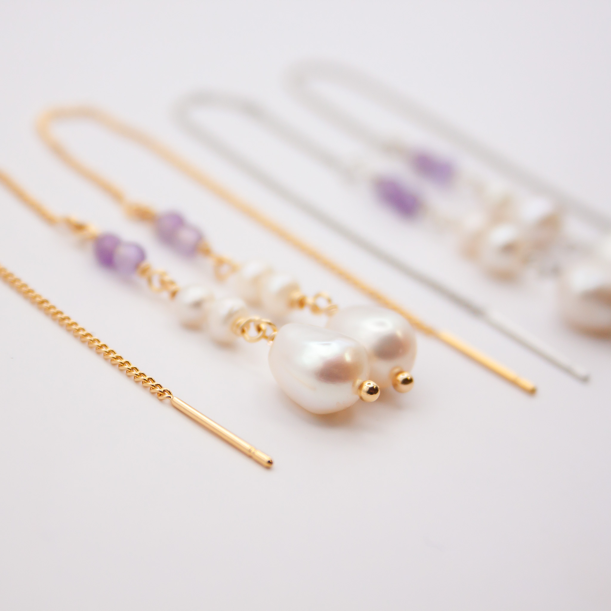 Gouden en zilveren doortrekoorbellen met paarse kralen en witte parels